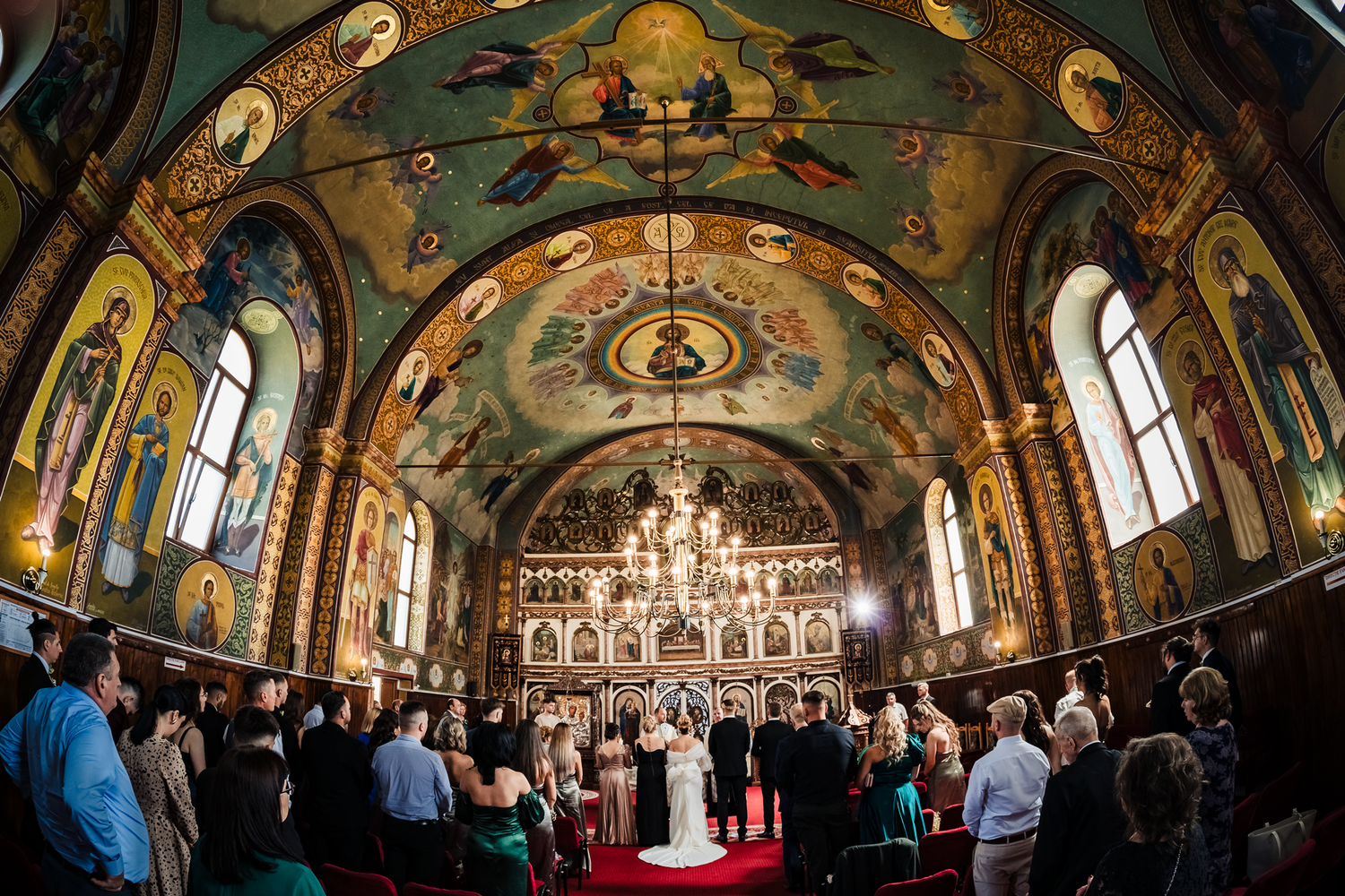 Panoramic view of beautifully painted church ceiling with religious iconography during ceremony.