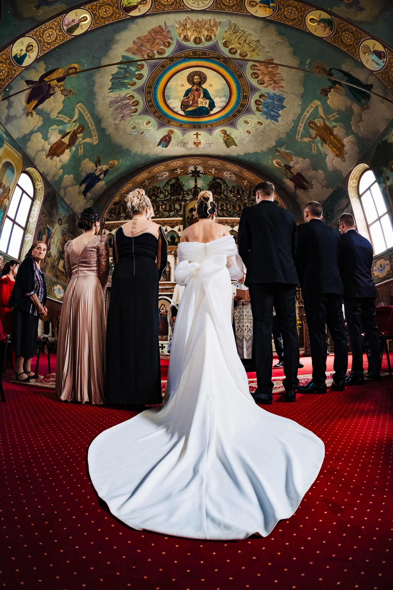 Stunning church interior with ornate frescoes and red carpet during wedding ceremony.