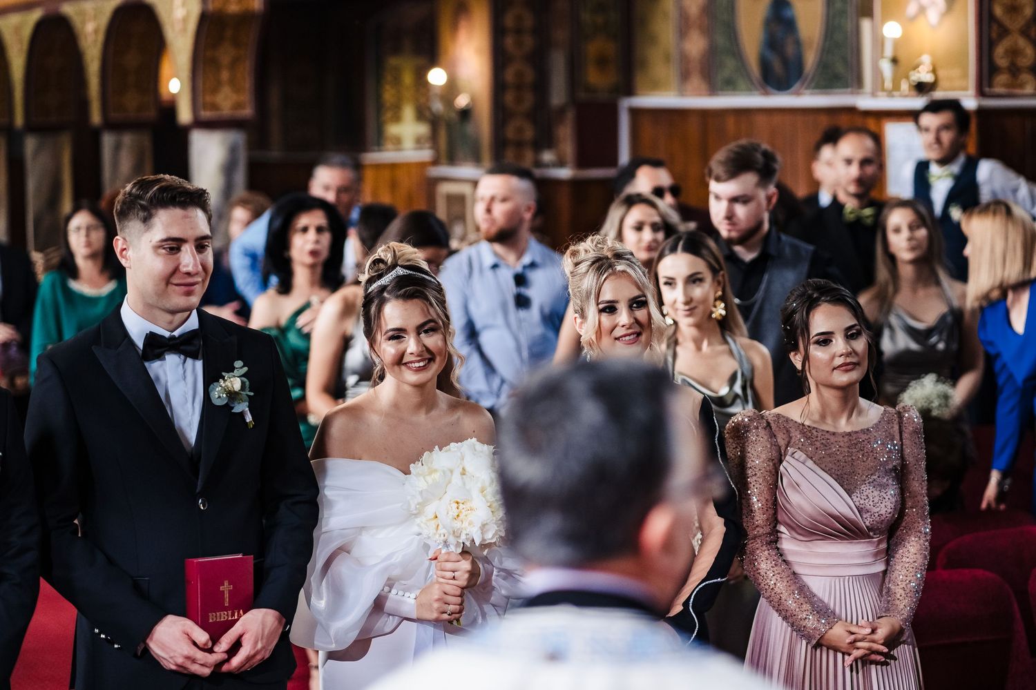 Wedding celebration inside ornate church with guests watching ceremony.