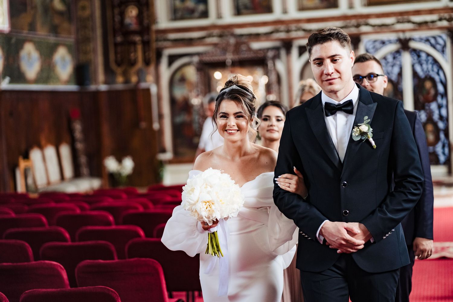 Wedding party stands in formal attire at a traditional church ceremony.