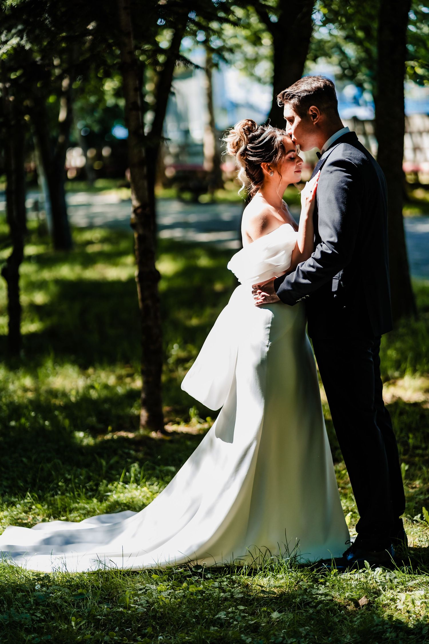 Wedding couple shares intimate moments among trees in a natural outdoor setting.