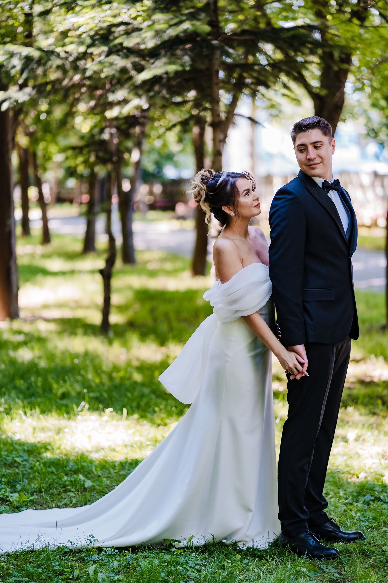 Wedding couple poses in a serene garden setting with flowing white gown and classic suit.