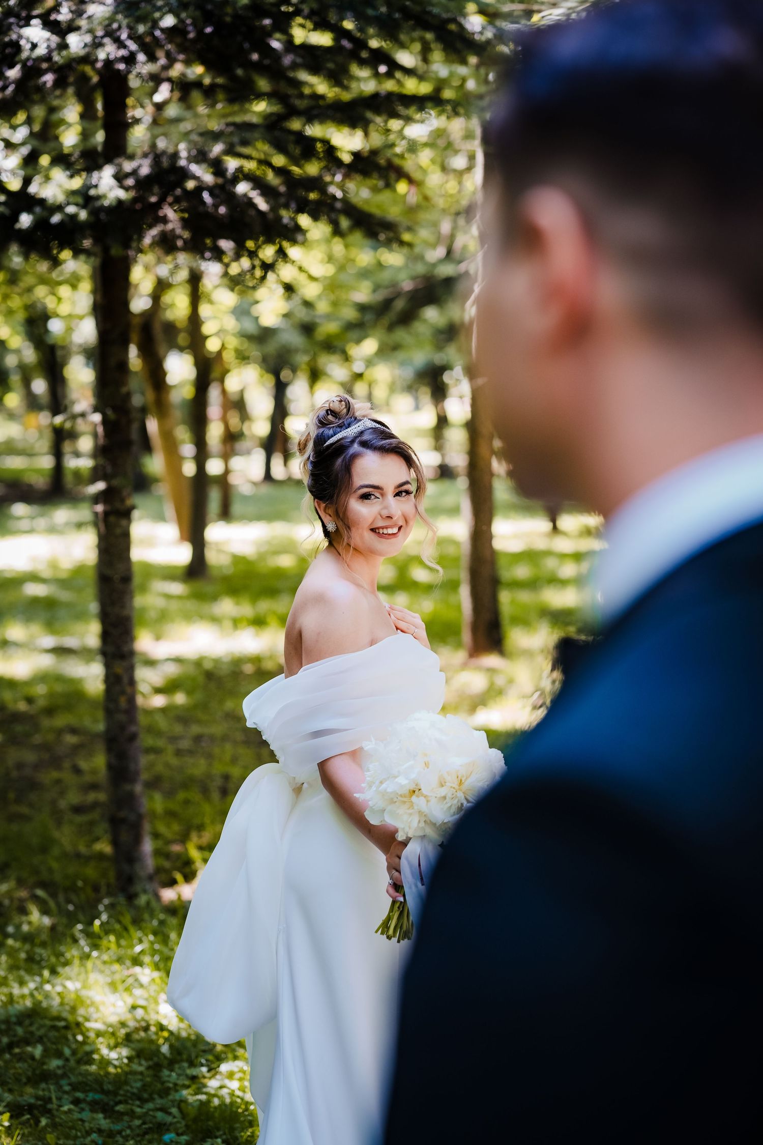 Romantic wedding portraits in a sunlit garden with flowing white dress and classic tuxedo.