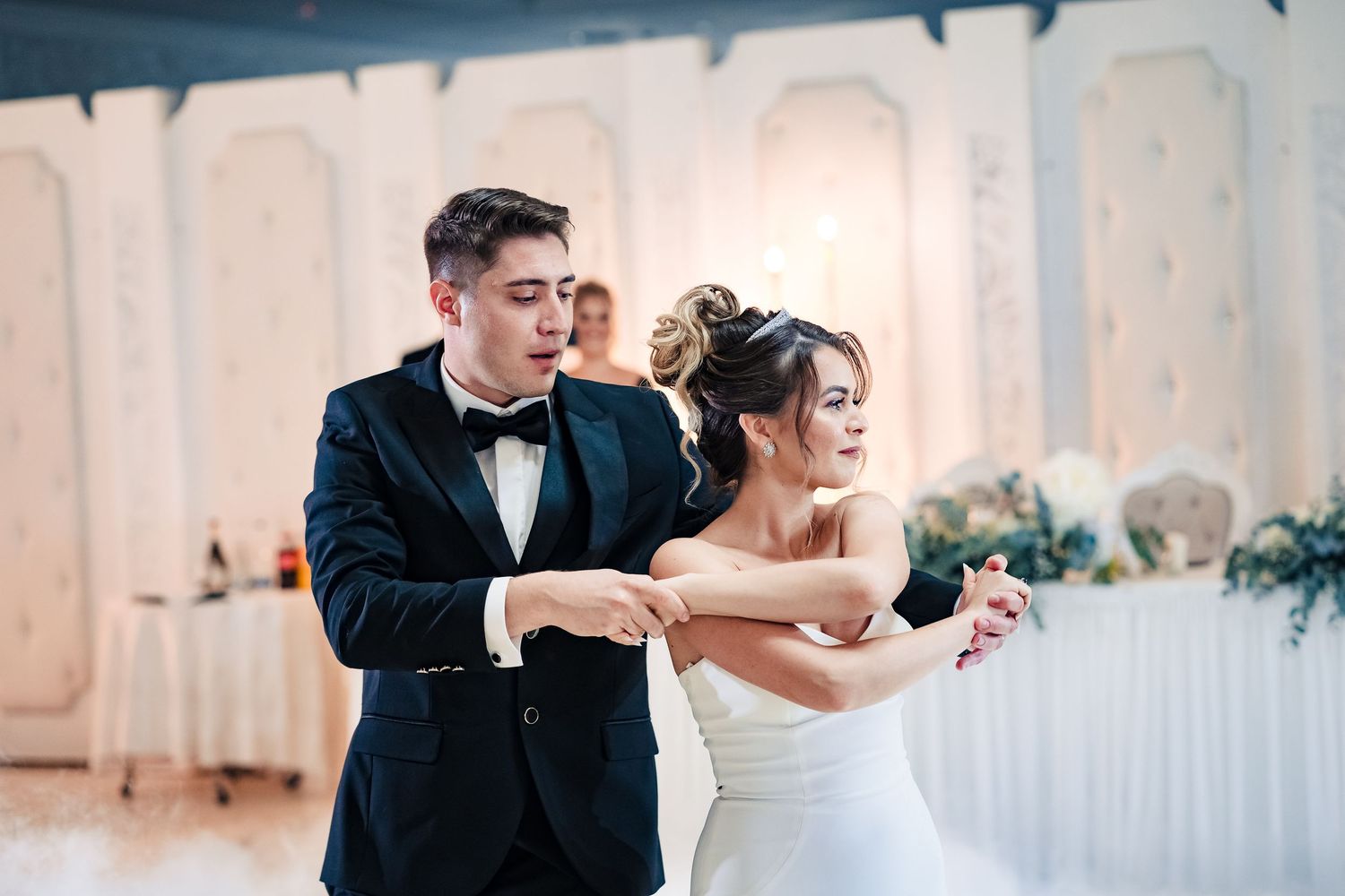 Elegant dance moves on display during a formal wedding reception with white decor.