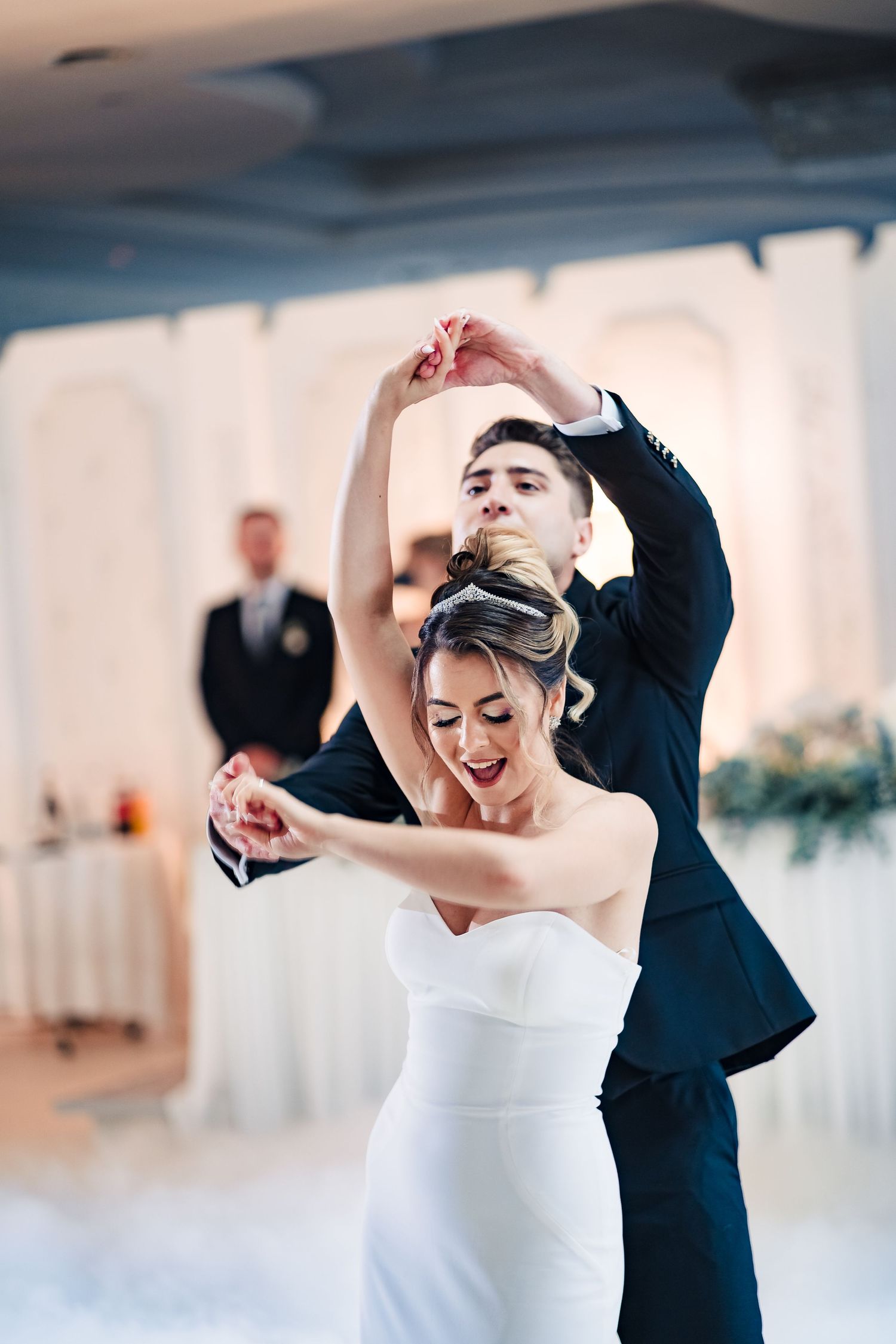 Elegant dance moves performed during a formal wedding reception with white decor and lighting.