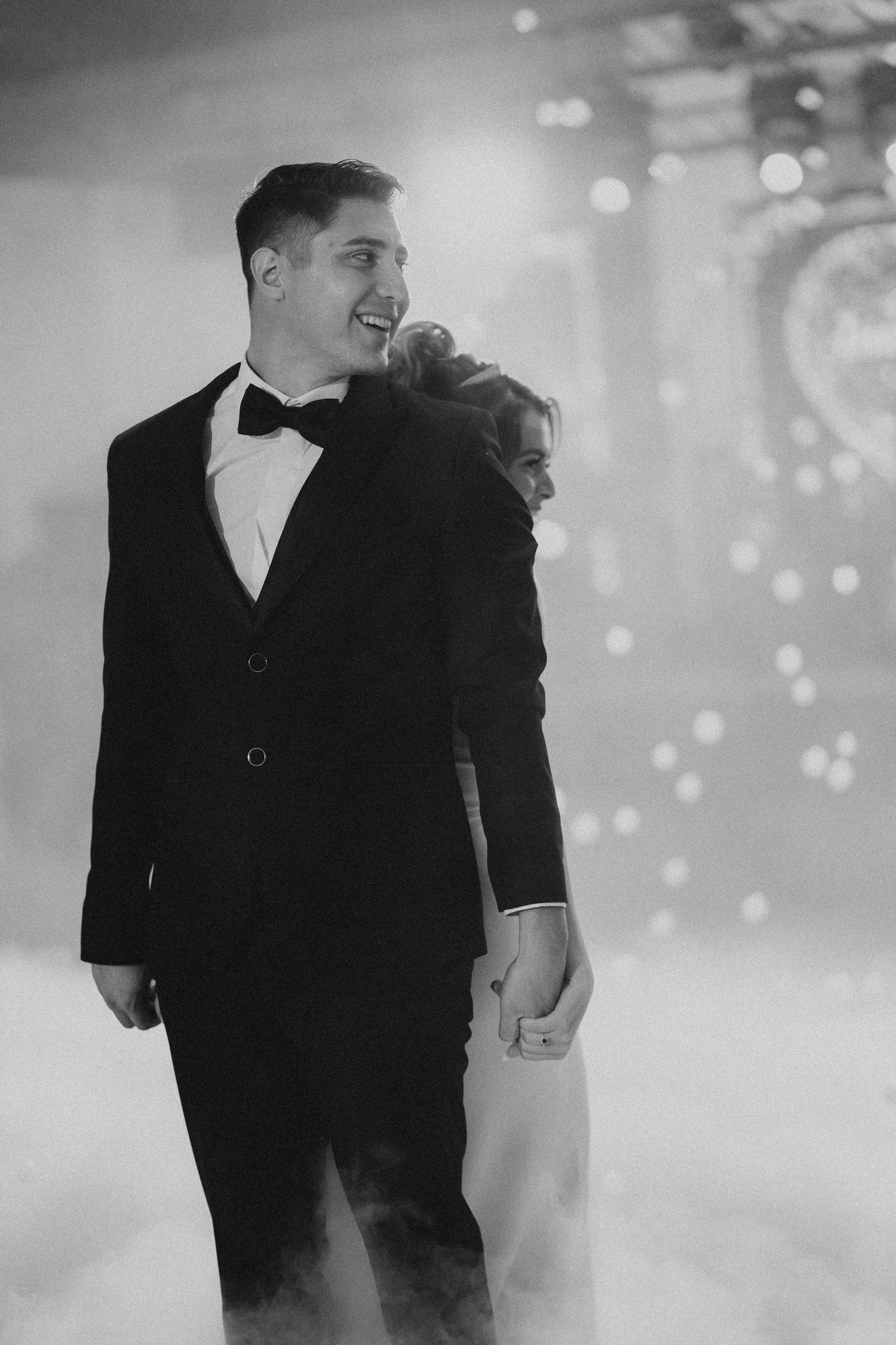 Couples dancing in formal black attire under soft lighting at an elegant event.