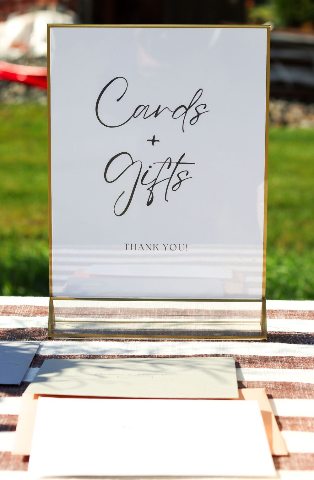 Elegant gold-framed sign displaying 'Cards & Gifts' in calligraphy with a thank you message.