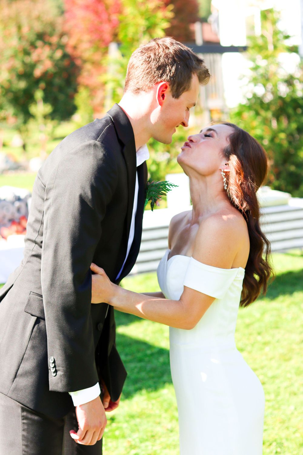 Romantic wedding portrait of couple in formal attire sharing tender moment outdoors.