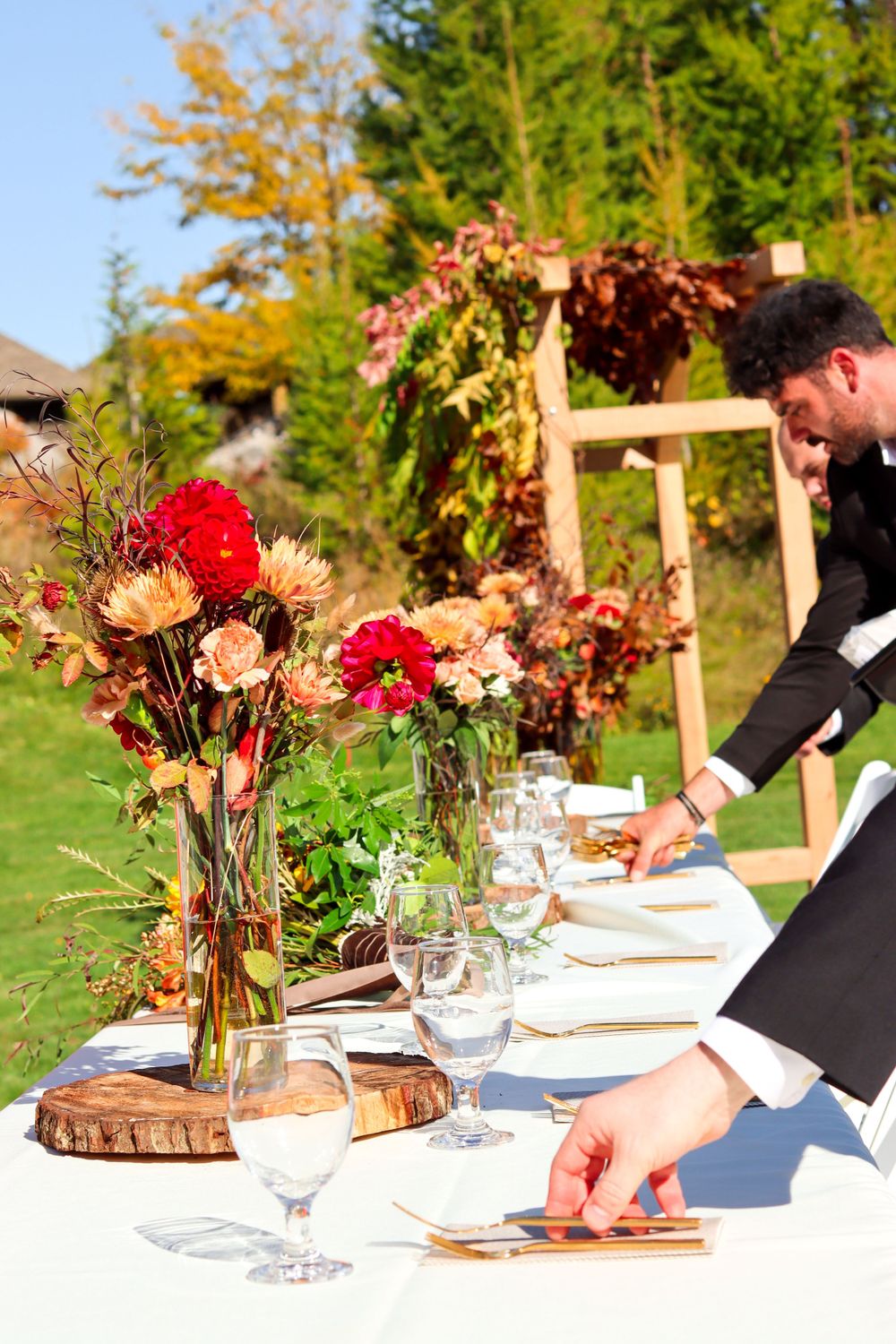Event table being set with autumn floral centerpieces and place settings.