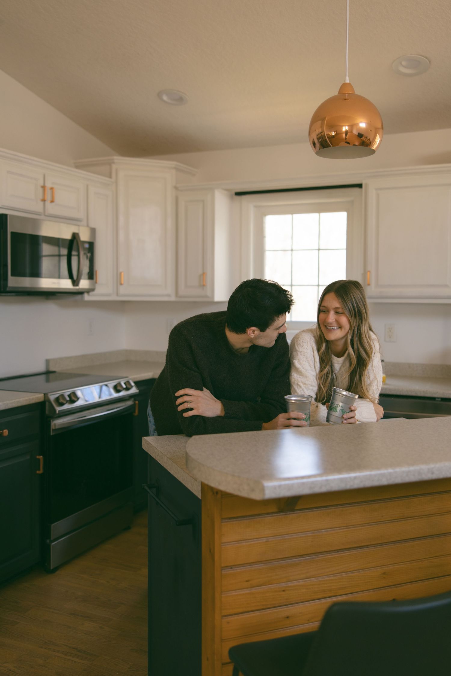 couple in kitchen of new home drinking natural light