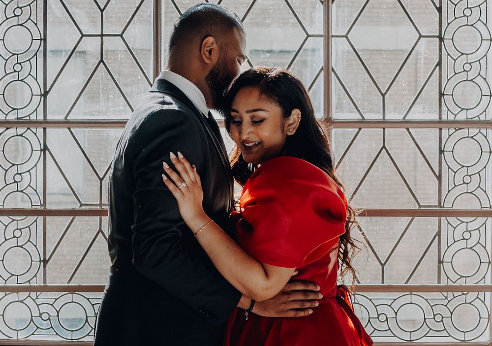 A tender moment captured between a couple against an art deco window pattern.
