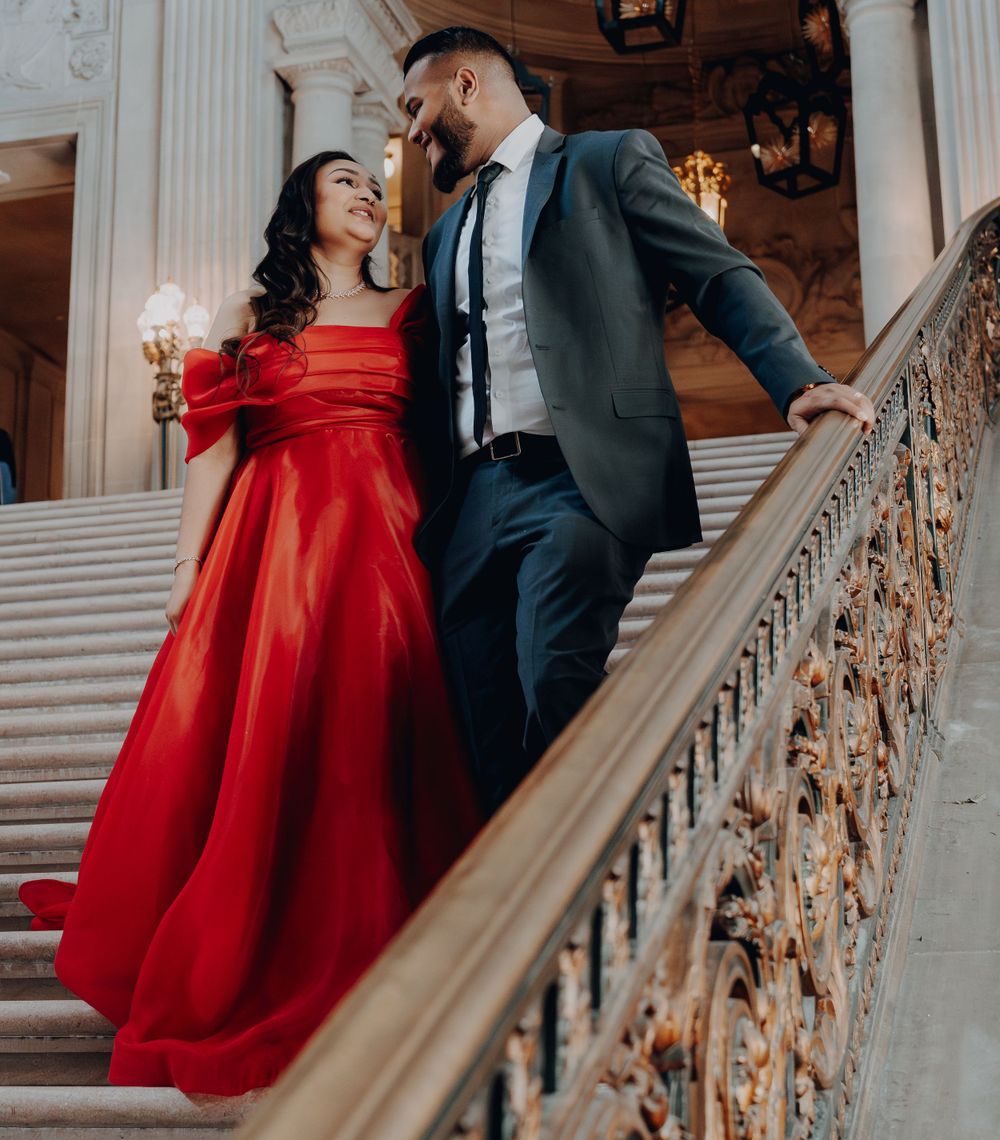 Couple sharing a romantic moment on an ornate marble staircase with decorative railings.