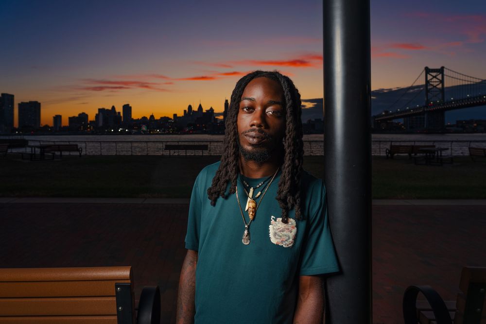 Healthcare professional stands in front of city skyline and bridge at sunset with warm orange sky.
