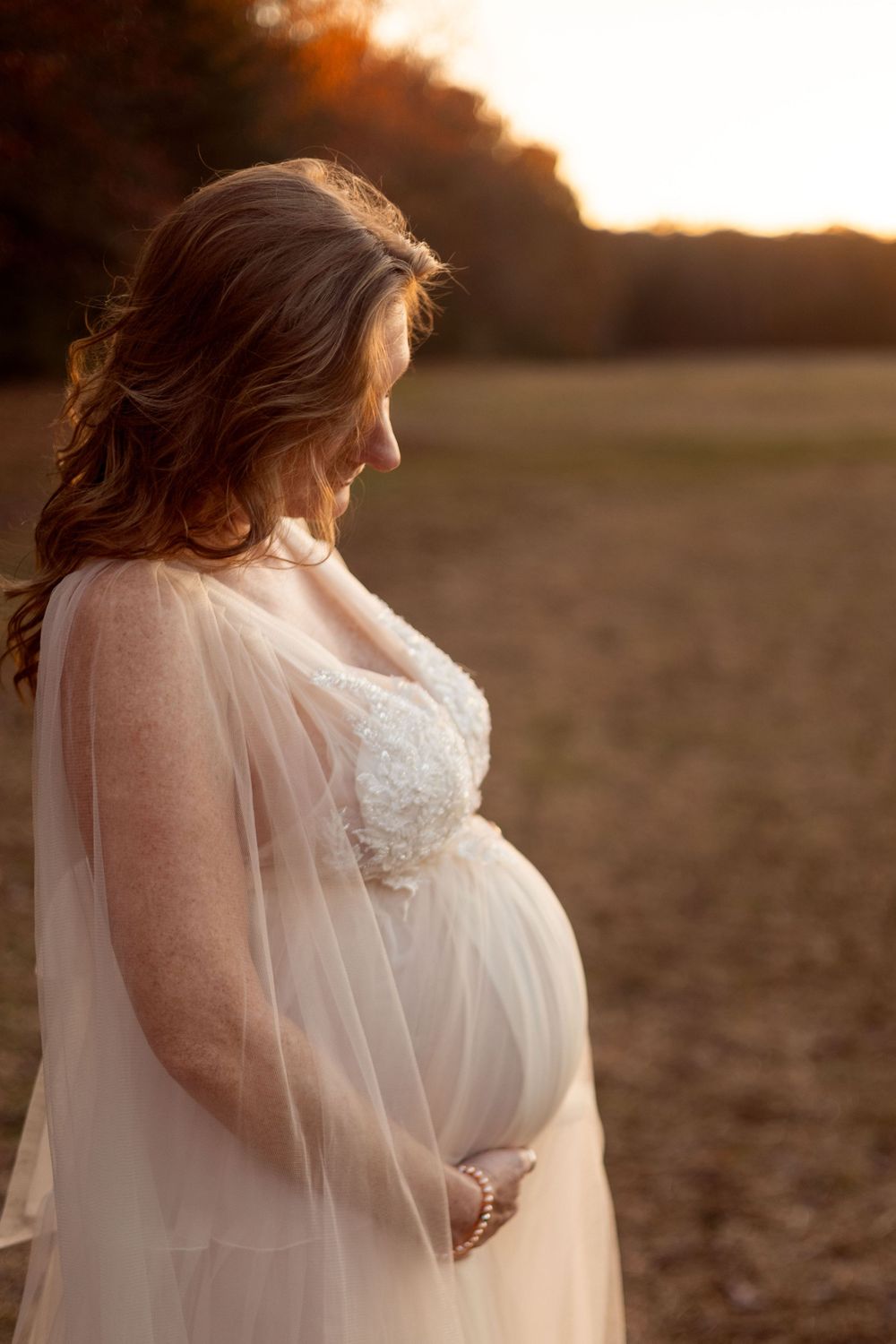 A pregnant woman looks down at her belly.