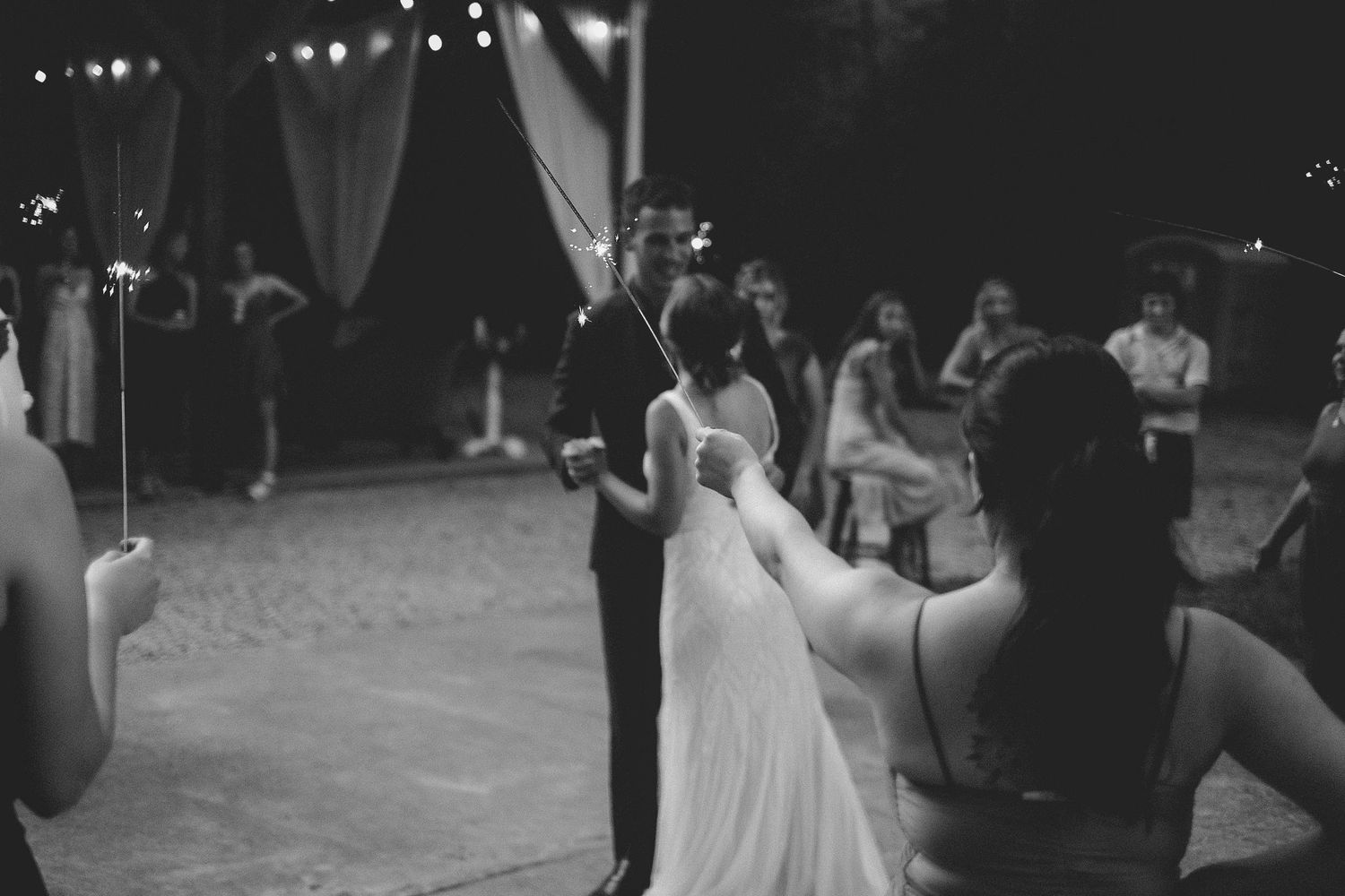 Candid black and white shot of wedding celebration with couple dancing.
