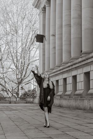 Black and white photo of a graduate tossing her cap in the air outside washington state capitol building taken by roy wa photographer.