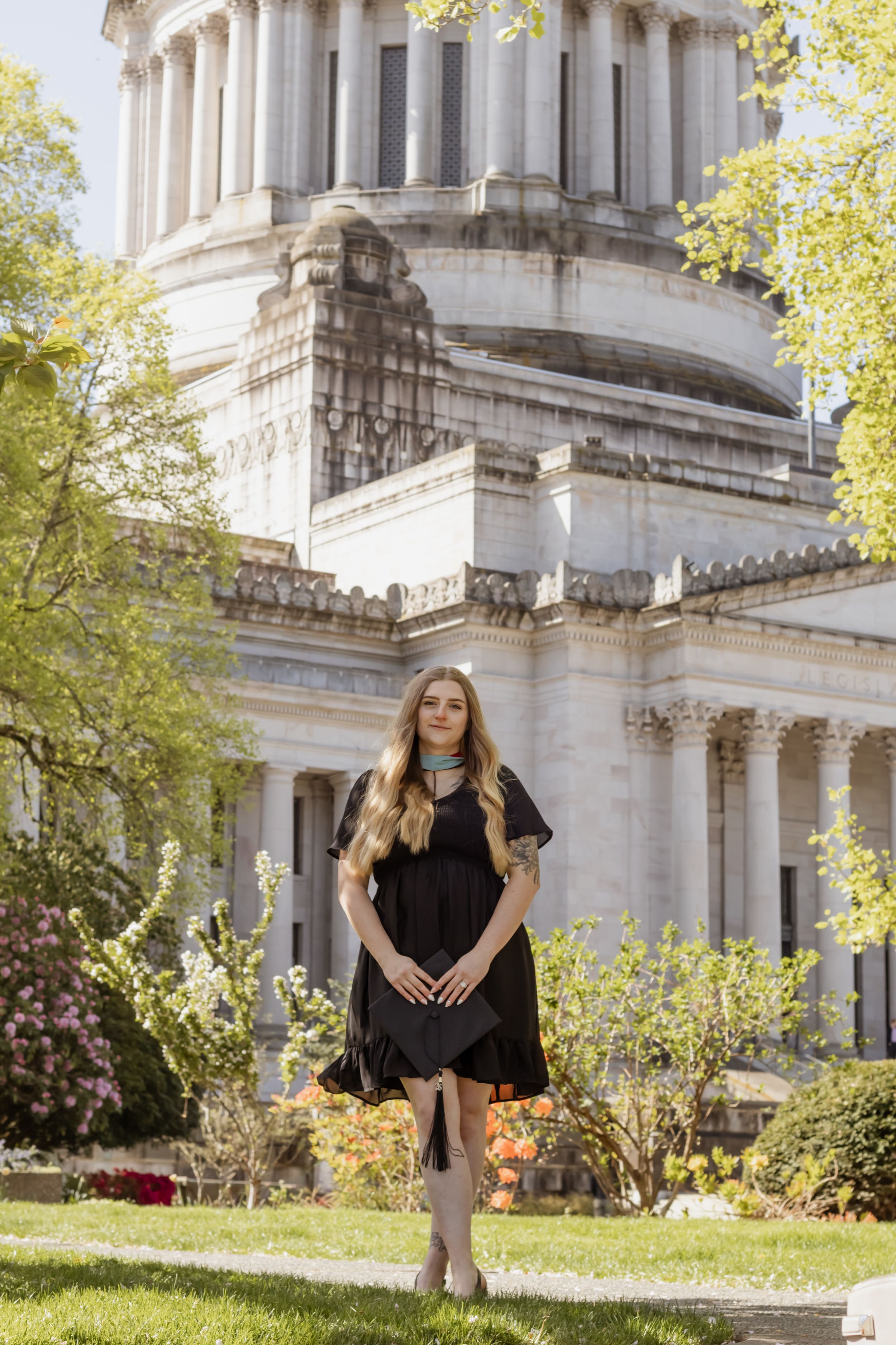 Young blonde woman in black dress standing in front of a grand Washington capitol building outdoors taken by Olympia photographer