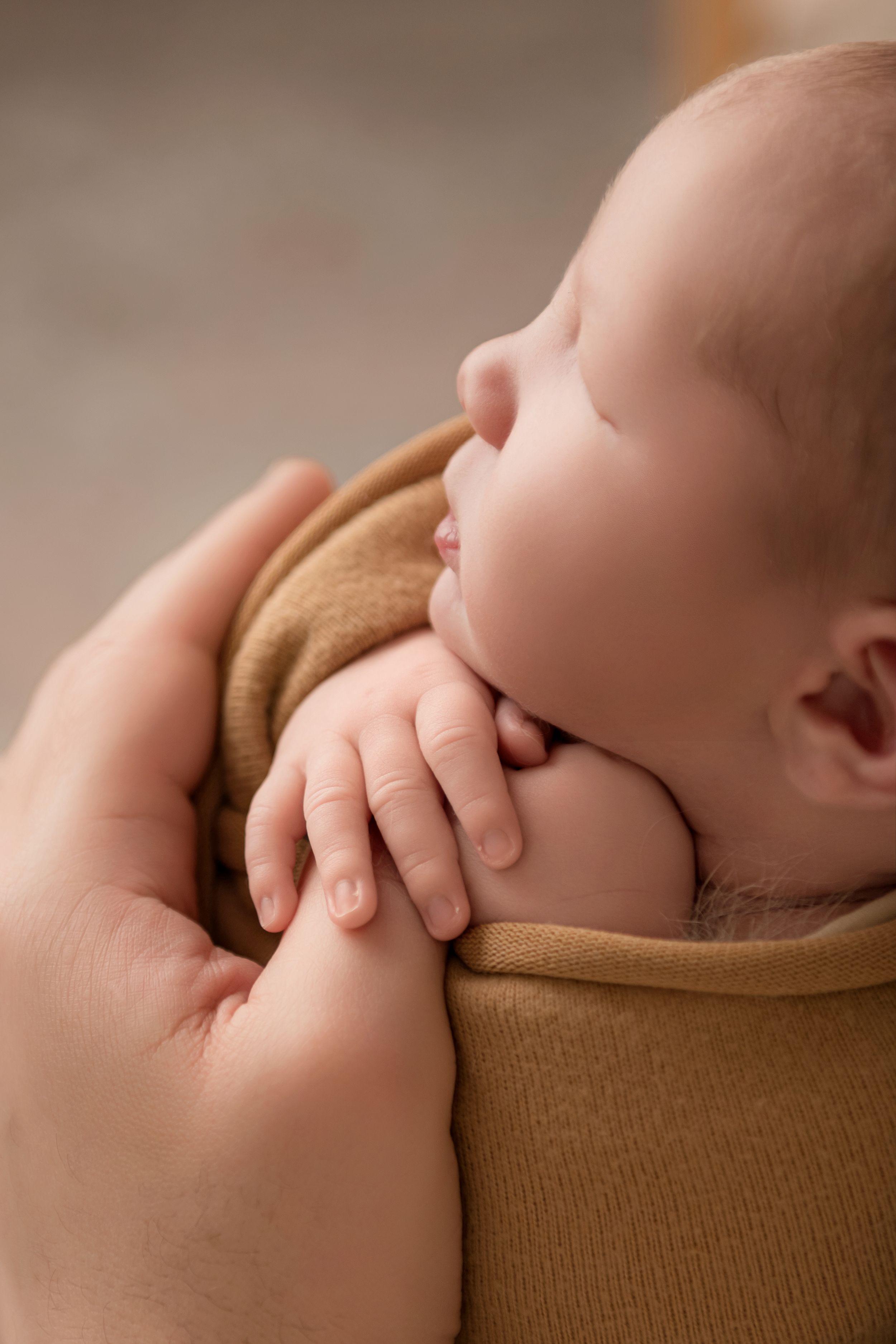Backlit, simple image of a newborn's hand around dad's thumb
