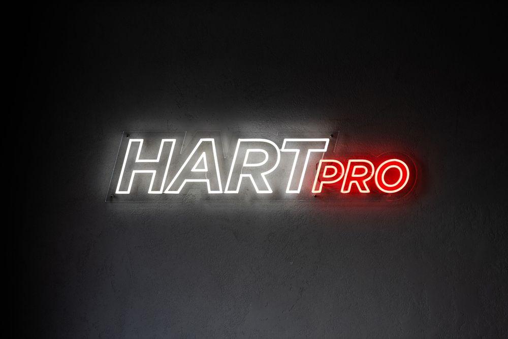 Neon HART PRO na ciemnej ścianie, białe litery HART i czerwony napis PRO. Fotografia biznesowa Lublin.
