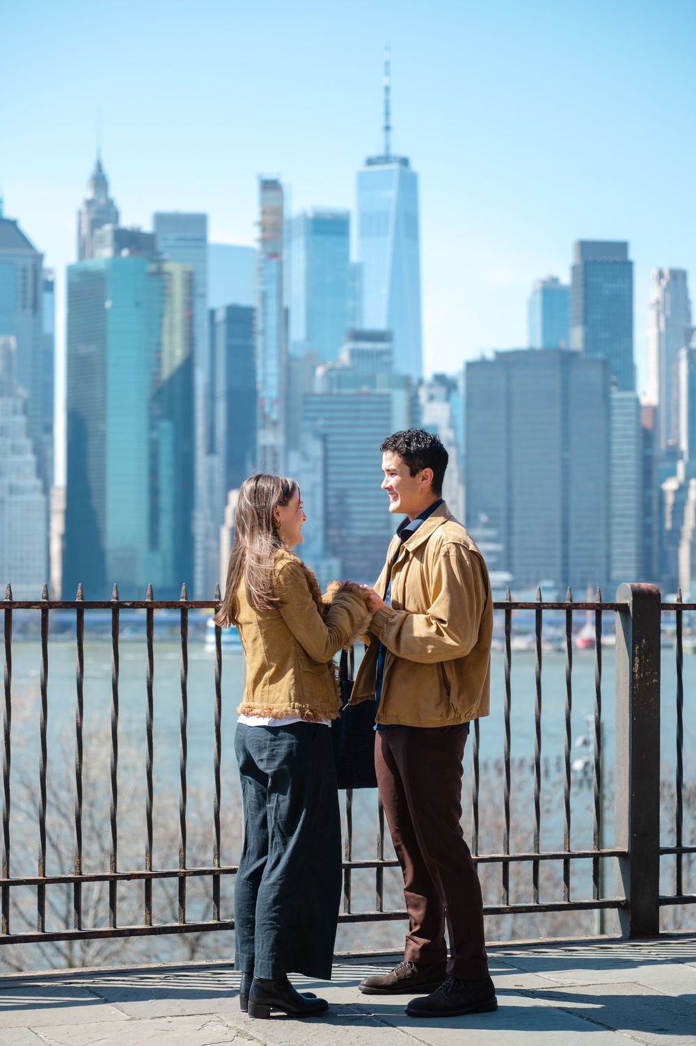 Couple holding hands facing each other with Manhattan skyline in the background.