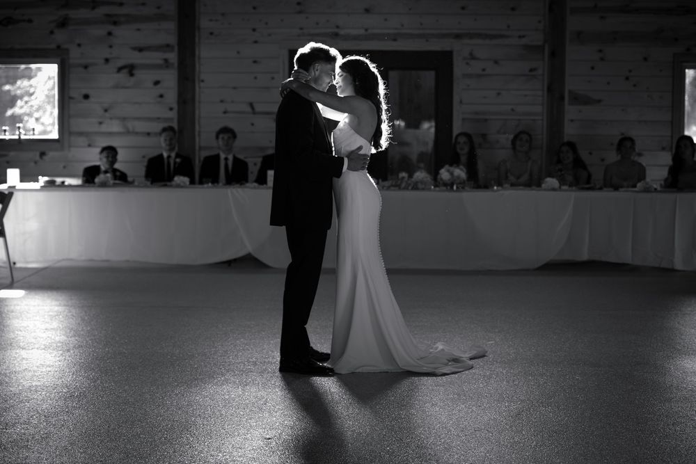 Black and white photo of bride and groom sharing first dance at wedding reception.