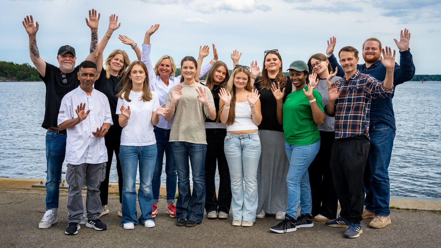 Företagsfotografering av Fotograf Jessica Lindqvist - en gruppbild av 13 glada medarbetare på Stavsnäs Krog, med händerna i luften.