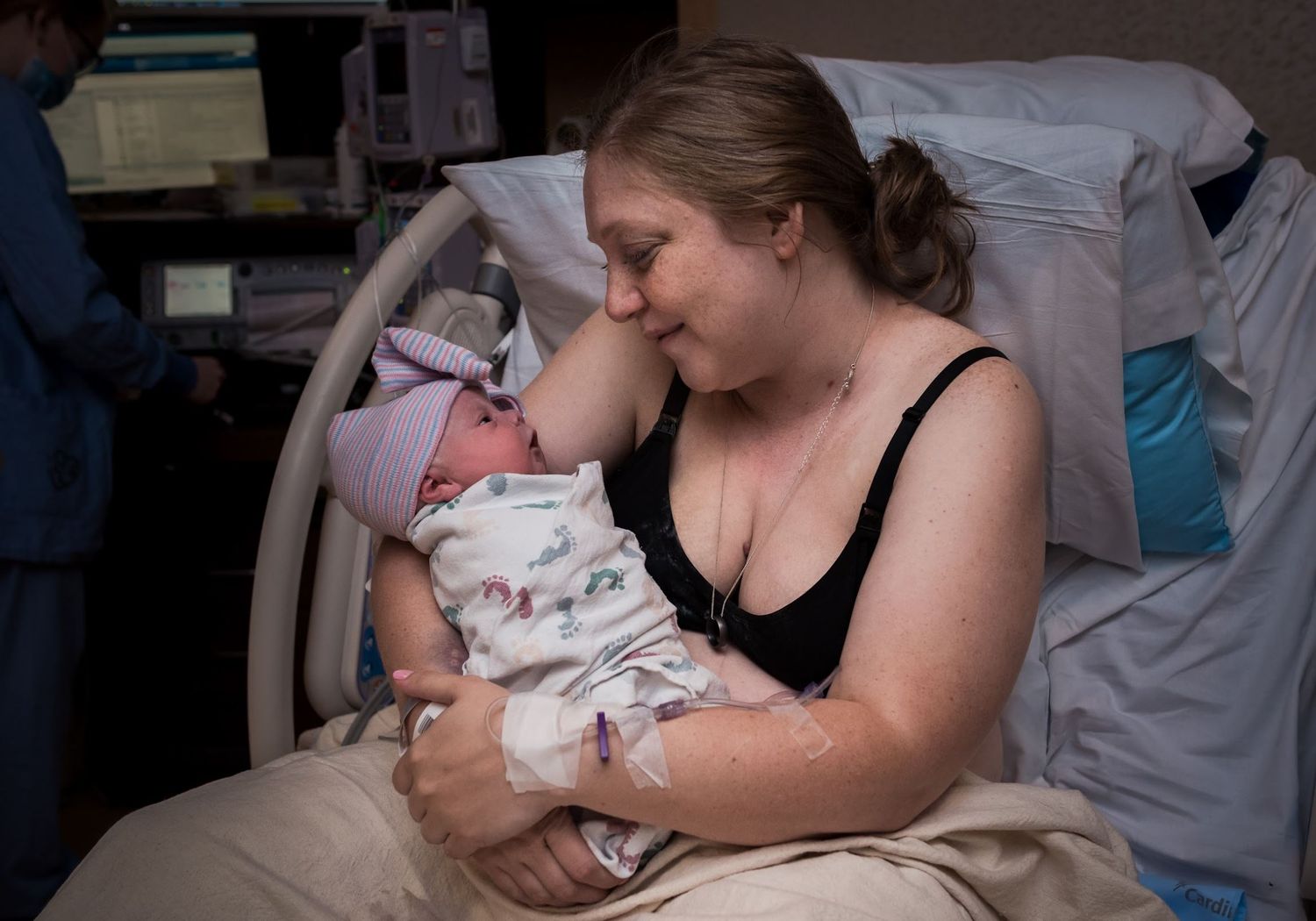 An intimate bonding moment with a newborn in a hospital recovery room.