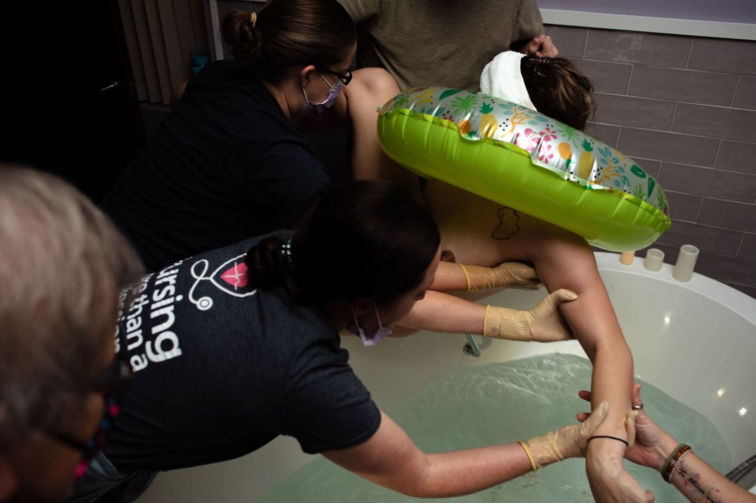 Mother is lifted out of the tub during the delivery of her baby