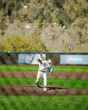 Baseball pitcher in white uniform mid-throw on a green field with Pepsi and Valley River Inn outfield signs.