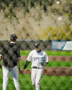 Two Titans baseball players in pinstripe uniforms exchange a handshake on the field during a game.