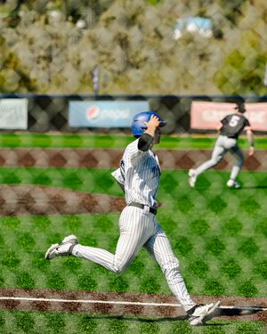 Baseball player in blue helmet and pinstripe uniform running bases during a sunny outdoor game.
