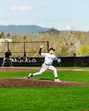 Baseball pitcher in white pinstripe uniform winds up for a pitch on the mound during a sunny outdoor game.