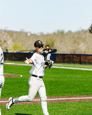 Baseball player in pinstripe uniform running and throwing ball on green field during sunny day game.