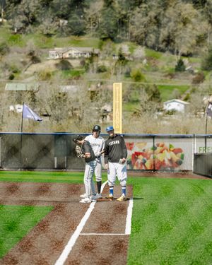 Two Titans baseball players stand together at first base on a sunny day during a game.