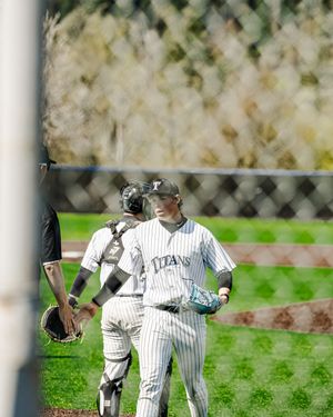 Two Titans baseball players in pinstripe uniforms walk together on the field, with a chain-link fence in the foreground.