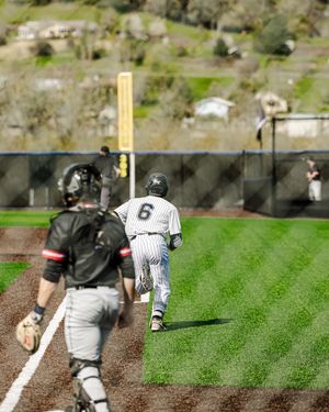 Baseball player number 6 runs bases as catcher approaches home plate during a sunny outdoor game.