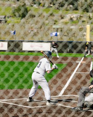 Baseball batter in white pinstripe uniform preparing to swing at home plate during a game.