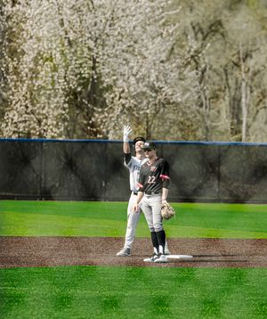 Baseball player #22 fields at second base with blooming spring trees in the outfield background.