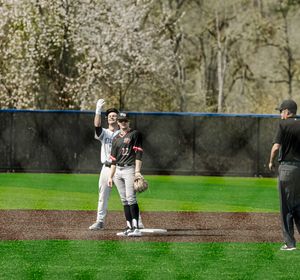 Two baseball players stand at second base while an umpire watches during a spring game.