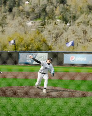 A Titans baseball pitcher winds up to throw during a game with a Pepsi advertisement in the background.