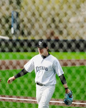 Titans baseball player in white pinstripe uniform wearing a batting helmet and glove on the field.