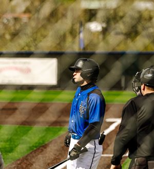 Baseball batter in blue uniform and black helmet standing at home plate during a game.