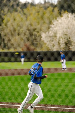 Baseball player in blue uniform jogging across the outfield during a game.