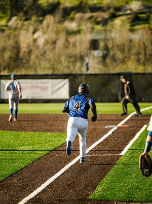 Baseball player number 4 in blue uniform runs the base path during a game on a well-maintained turf field.
