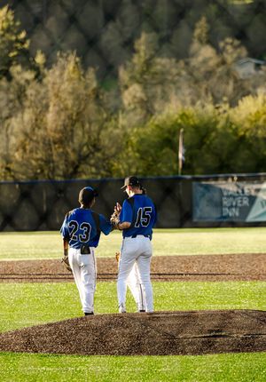Two baseball players in blue uniforms, numbers 23 and 15, conferring on the pitcher's mound during a game.