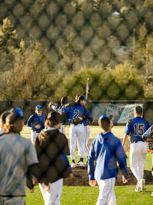 Baseball players in blue uniforms celebrate on field, player number 2 hugged by teammate near home plate.