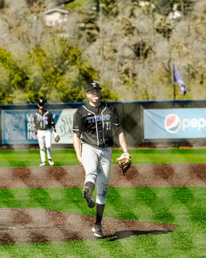 Baseball pitcher in Titans uniform jogging on field during sunny day game with Pepsi advertisement in background.