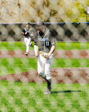 Baseball player number 11 in Titans uniform fields ball on sunny green diamond during game.