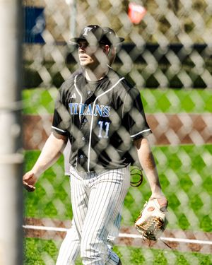 Baseball player wearing Titans jersey number 11 walks on field holding glove during sunny day game.
