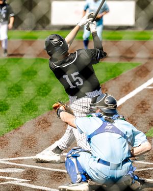 Baseball batter number 15 swings at a pitch while catcher crouches behind home plate during a game.